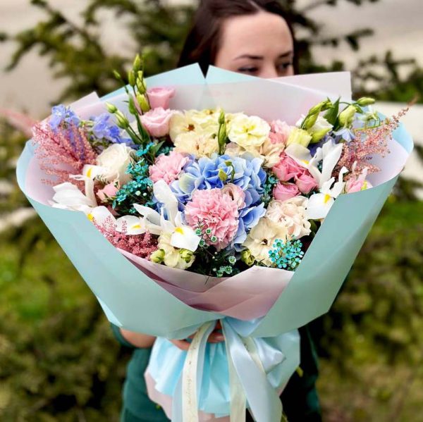 A close-up view of the "Radiant Floral Elegance" bouquet, showcasing a harmonious blend of hydrangeas, ranunculus, irises, lisianthus, dianthus, astilbe, and roses, radiating timeless elegance and floral sophistication.