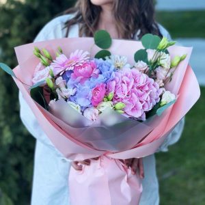 A close-up view of the "Enchanted Garden Harmony" bouquet, showcasing the vibrant colors and lush blooms of hydrangeas, ranunculus, gerberas, eustoma, and the elegant foliage of eucalyptus.
