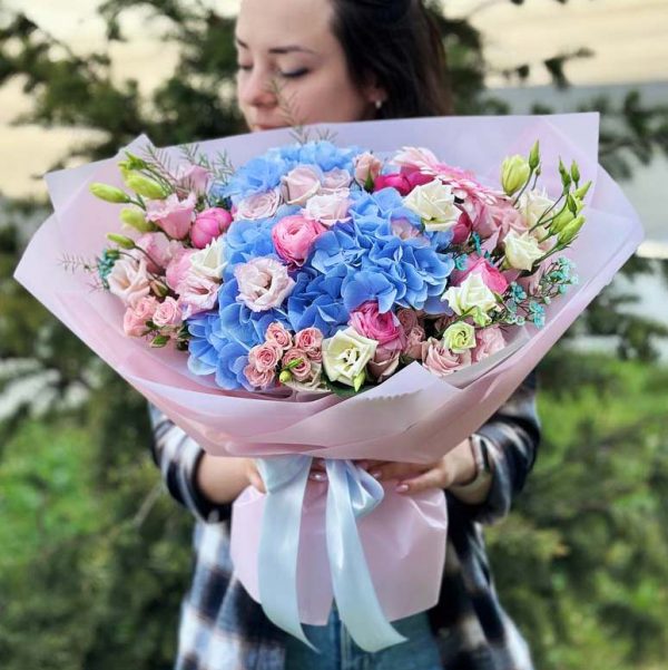 A radiant bouquet showcasing hydrangeas, gerberas, ranunculus, spray roses, lisianthus, and oxypetalum, perfect for adding elegance to any occasion.