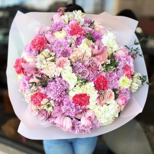 Spring Symphony bouquet featuring hydrangeas, tulips, chrysanthemums, spray roses, orchids, dianthus, alstroemeria, eucalyptus, and wax flowers